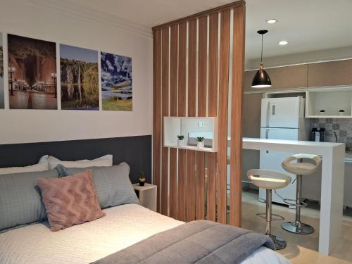 a bedroom with a bed and a small kitchen at Lindo studio equipado em apartamento clube com piscina aquecida e academia no centro de Curitiba - MID Home in Curitiba