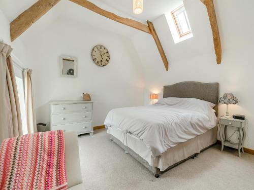 a bedroom with a bed and a clock on the wall at Myrtle Cottage in Saint Just in Roseland