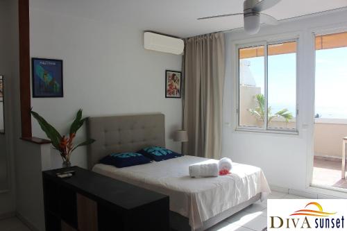 a bedroom with a bed and a large window at Tahiti Diva Sunset studio in Papeete