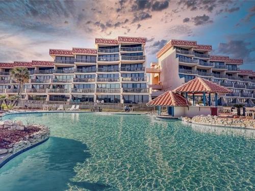 un complexe avec une piscine en face d'un bâtiment dans l'établissement Mayan Princess 101 Beachfront Resort, à Port Aransas
