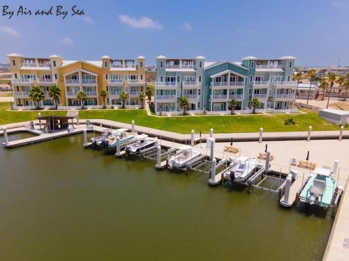 a marina with boats in the water next to buildings at By Air & By Sea in Port Aransas