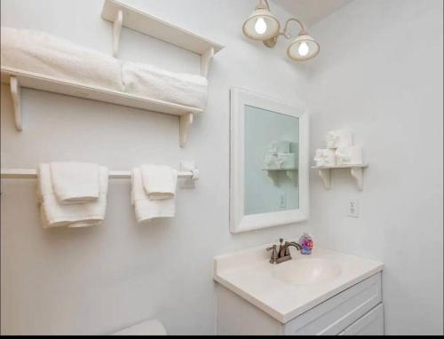 a white bathroom with a sink and a mirror at Wood Fire-pit! BBQ Grill! Cal King bed! Pets OK! Washer & Dryer! Wifi! in Charlotte