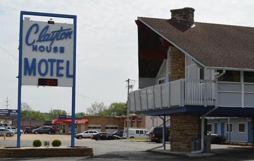 un panneau de motel dans un parking à côté d'une maison dans l'établissement Clayton House Motel, à Loves Park