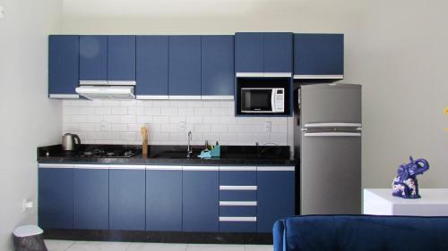 eine Küche mit blauen Schränken und einem Kühlschrank in der Unterkunft Recanto aconchegante no Campeche Apart 02 - 50m da praia - in Florianópolis