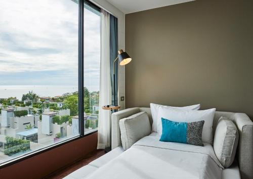 een slaapkamer met een bank en een groot raam bij Loligo Resort Hua Hin in Hua Hin