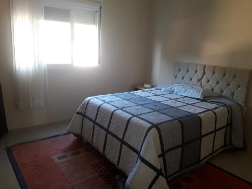 1 dormitorio con 1 cama con manta azul y blanca en UNIJUI, en Ijuí
