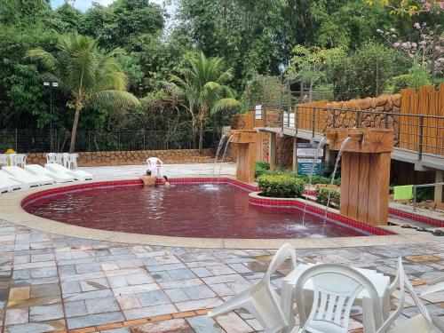 a pool with a fountain with white chairs around it at Flat 902 Golden Dolphin Express in Caldas Novas