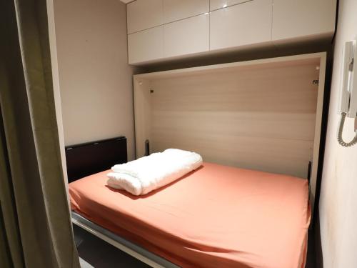 Cette petite chambre comprend un lit avec des draps blancs. dans l'établissement Studio au Centre des Gets, Proche Remontées, Confort Moderne - 4 Couchages - FR-1-623-194, aux Gets