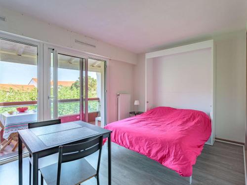 ein Schlafzimmer mit einem rosa Bett und einem Tisch in der Unterkunft Studio Anglet, 1 pièce, 2 personnes - FR-1-3-596 in Anglet