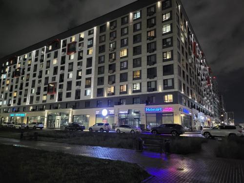 un edificio con coches aparcados delante de él por la noche en Толе Би 57 - ТРЦ Хан Шатыр en Astaná