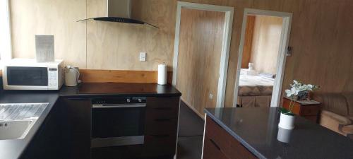 a kitchen with a black counter top and a microwave at Tongariro Estate in National Park