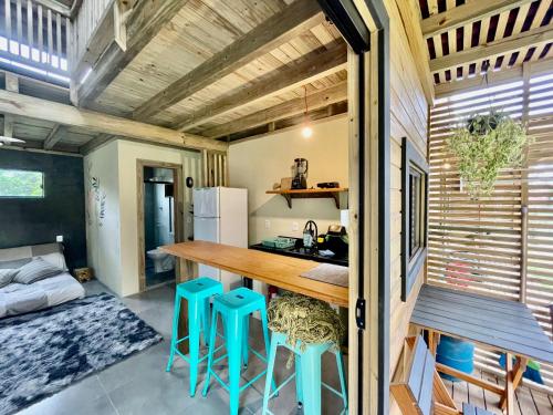 uma pequena casa com uma cozinha com uma mesa e bancos em Rosa Lodge Lofts em Praia do Rosa