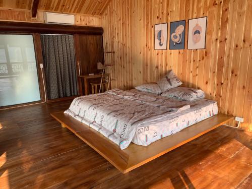 1 dormitorio con 1 cama en una habitación de madera en Hồ Tằm Homestay, en Hòa Bình