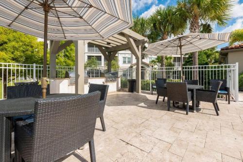 un patio con tavoli, sedie e ombrelloni di Luxury Family Resort Styled Apartment Near Disney a Orlando