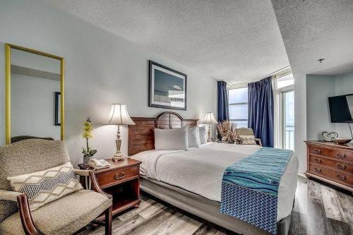 a bedroom with a bed and a chair and a window at Spectacular Ocean and Coastline Views Condo CB 14th Floor in Myrtle Beach