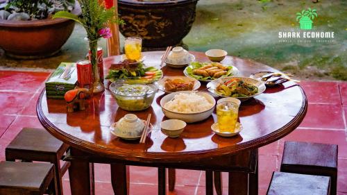 una mesa de madera con tazones de comida. en SHARK ECOHOME BẾN TRE en Ấp Phong Phú