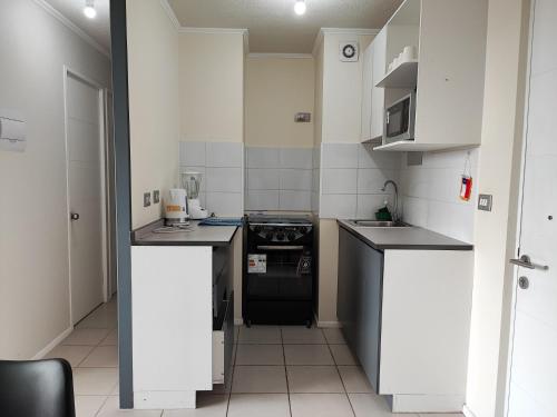 a small kitchen with black appliances and white cabinets at Departamento en Temuco in Temuco