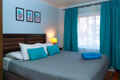 a bedroom with a bed with blue pillows and a window at Tagle Casa del Lado Santiago Providencia in Santiago