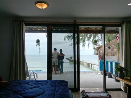 a couple standing in a bedroom looking out at the ocean at Sunny Bungalow in Koh Rong Sanloem