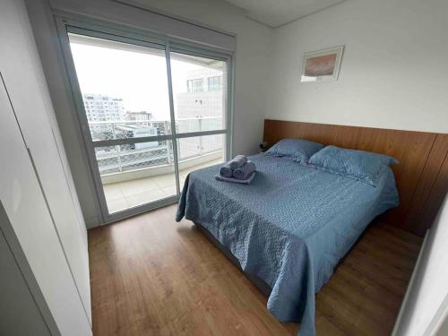 a bedroom with a bed and a large window at PRAIA BRAVA 3 QUARTOS, CONDOMÍNIO COMPLETO in Itajaí