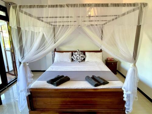 a bedroom with a canopy bed with white curtains at Shan Star Weligama in Weligama