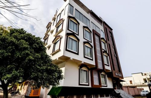 un edificio blanco y marrón con un árbol delante de él en Hotel Kanchan Residency, en Kota