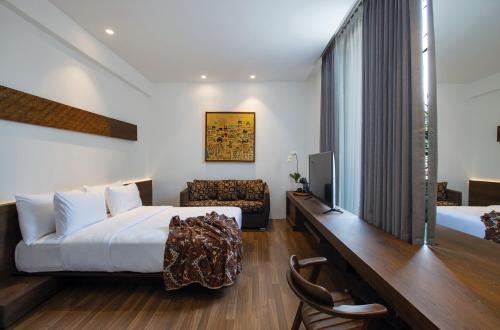 Schlafzimmer mit einem Bett und einem Schreibtisch mit einem TV in der Unterkunft Miers Kuningan, ARTOTEL Curated in Jakarta