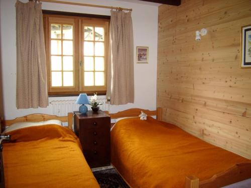 two beds in a bedroom with wooden walls and a window at Chalet 5 chambres, 9 pers, wifi, 1 animal, non fumeur - FR-1-733-144 in Crest-Voland