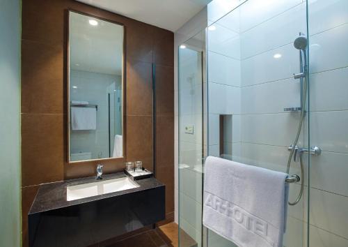 ein Bad mit einem Waschbecken und einer Glasdusche in der Unterkunft Miers Kuningan, ARTOTEL Curated in Jakarta