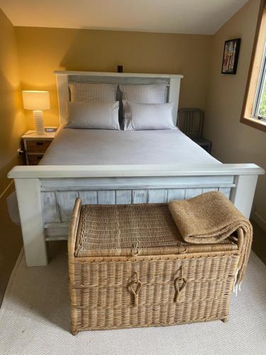 1 dormitorio con 1 cama blanca grande y cesta de mimbre en Kaingarua Retreat, en Kerikeri