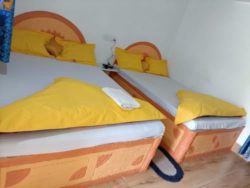 deux lits jumeaux dans une chambre avec des oreillers jaunes dans l'établissement Chamtaburu Eco Resort, à Bāghmundi