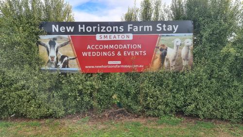 a sign hanging from a hedge with animals on it at New Horizons Farm Stay in Smeaton