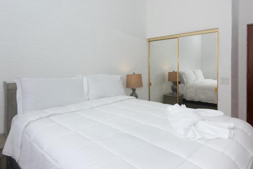 a large white bed in a bedroom with a mirror at Pineapple Villa 442 condo in Roatan