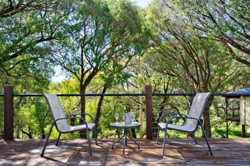 two chairs and a table on a deck with trees at Karriview in Gracetown