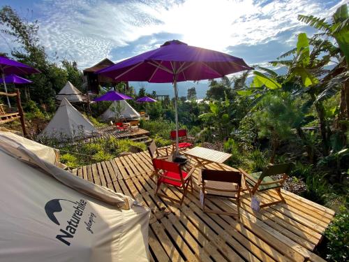 a wooden deck with chairs and an umbrella at Khu nghỉ dưỡng Kala Campark in Tali Teurlou