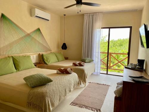 Habitación de hotel con 2 camas y ventana en Sunsteps casa holbox, en Isla Holbox