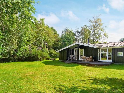 una casa verde con terraza y sillas en un patio en 5 person holiday home in G rlev en Gørlev