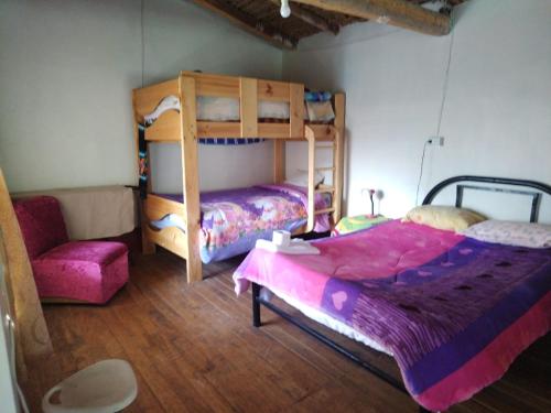1 dormitorio con 2 literas y 1 silla en Casa de Campo-Hospedaje Munay Wasi, en Tarma