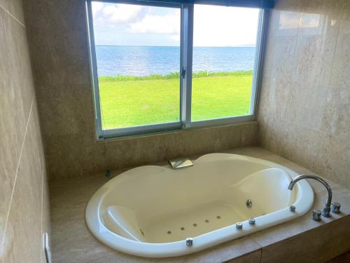 a bath tub in a bathroom with a window at エコヴィレッジ西表 Eco Village Iriomote in Iriomote