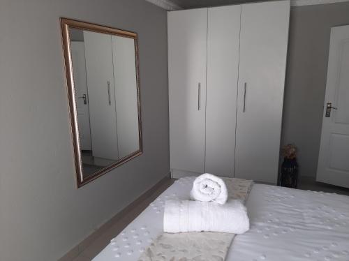 a bedroom with a bed with a mirror and towels at Bonfai Residence in Ermelo