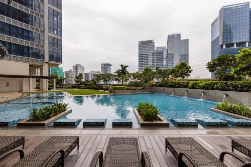 een groot zwembad met stoelen en gebouwen bij Spacious Cozy Condo with Gym and Shared Pool in Manilla