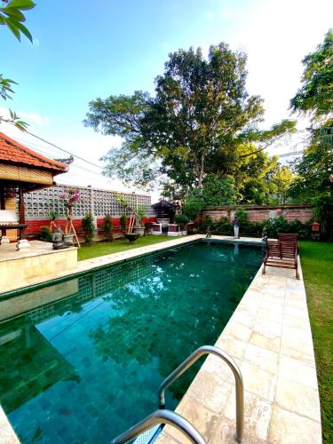 a swimming pool with a bench in a yard at Puri Ayu in Canggu