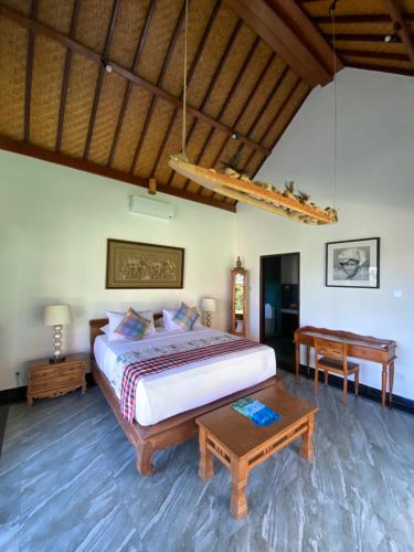 ein Schlafzimmer mit einem großen Bett und einem Tisch in der Unterkunft Puri Ayu in Canggu