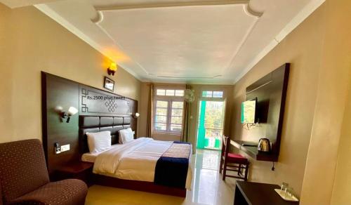 a hotel room with a bed and a chair at Green Hotel in Dharamshala