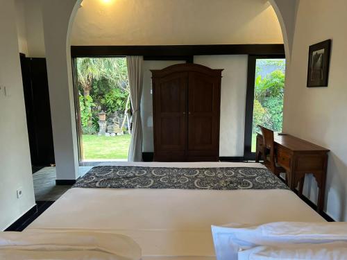 a bedroom with a bed and a desk and a window at Puri Ayu in Canggu