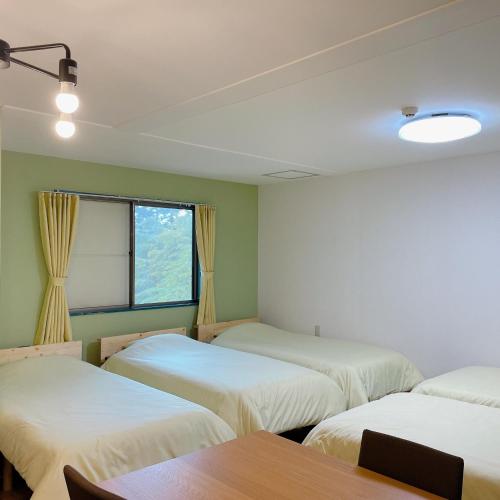 three beds in a room with a table and a window at Cate no mori - Vacation STAY 52818v in Shime