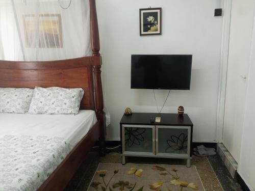 um quarto com uma cama e uma televisão de ecrã plano em Paradise Apartment em Mombaça