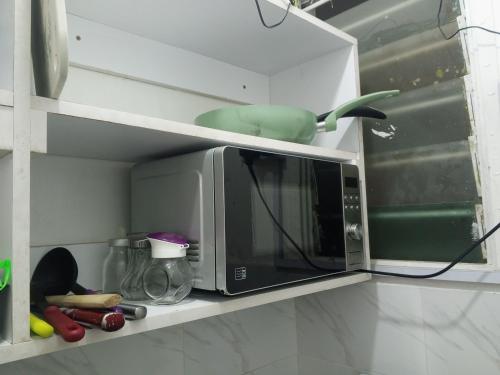 a microwave on a shelf in a kitchen at Paradise Apartment in Mombasa