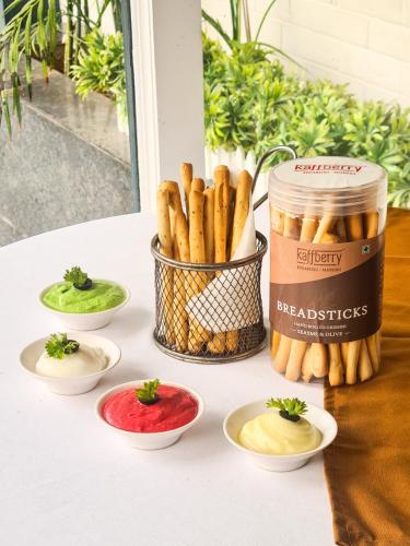 a table with plates of food and a jar of breadsticks at Kaffberry Cafe & Homestays in Kūd