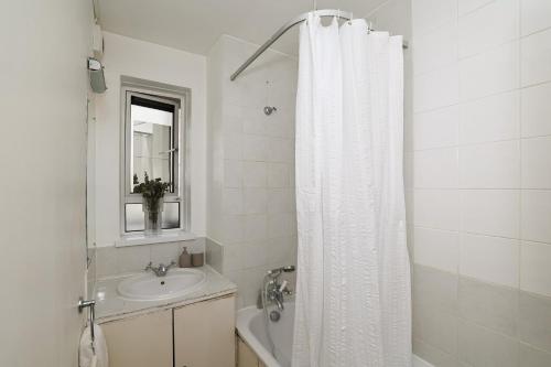 a bathroom with a white shower curtain and a sink at Spacious 2 bedroom Apartment In Holborn in London